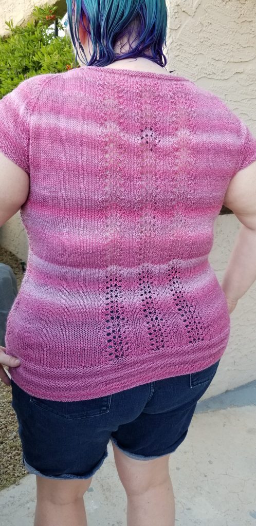 Description: Back view of Stephanie wearing a knitted pink variegated top with lace panels; the back has 3 lace panels, instead of 1.