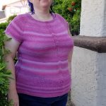 Stephanie wearing a knitted cap-sleeve raglan top in pink variegated yarn.