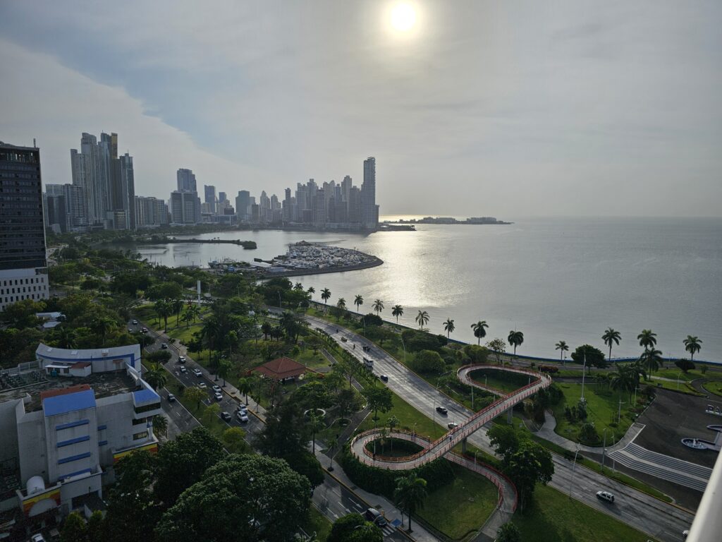 The city skyline and coast of Panama City, with the sun reflecting off of the ocean.