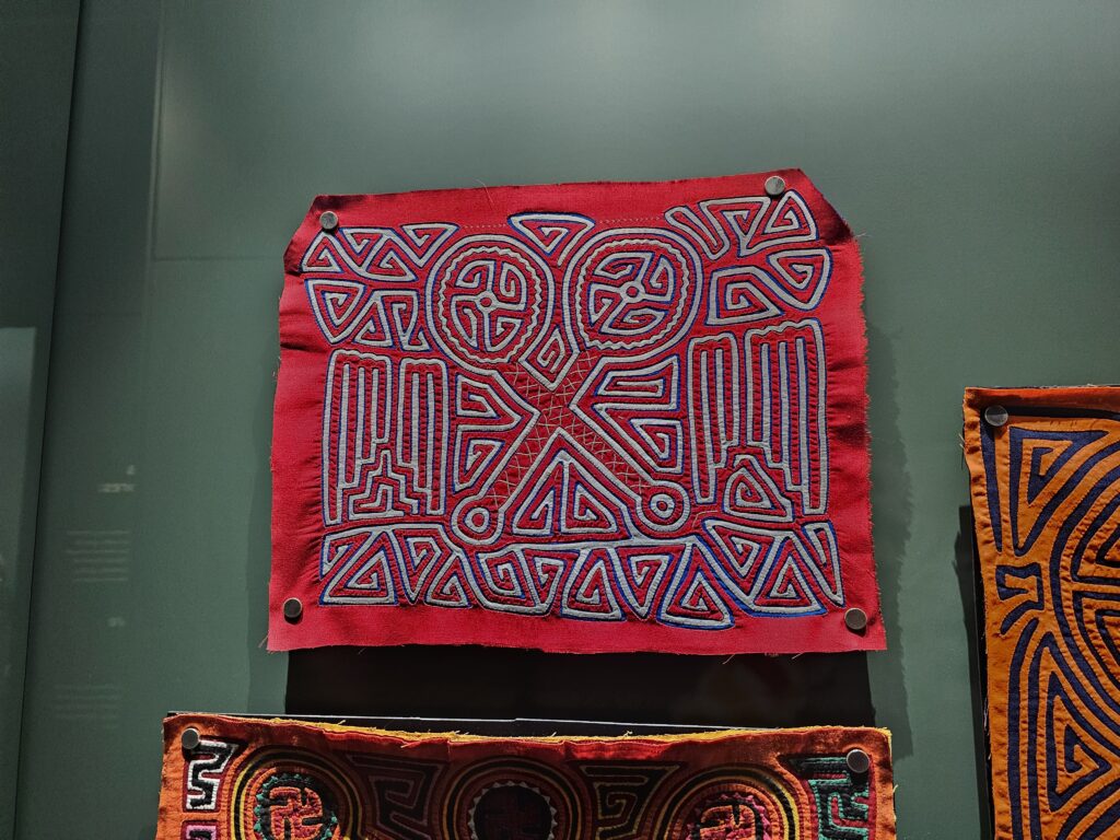 A red rectangular fabric with an intricate design in blue relief