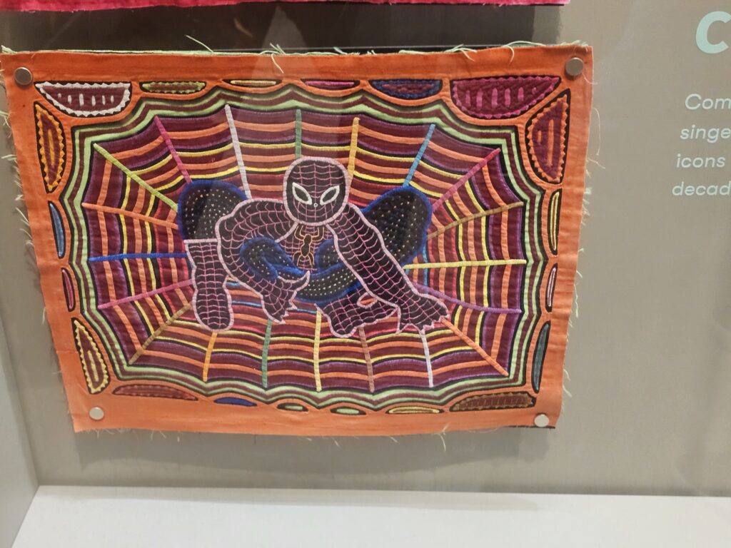 A mola in orange with many layers and colors, depicting Spiderman in the center of a web.