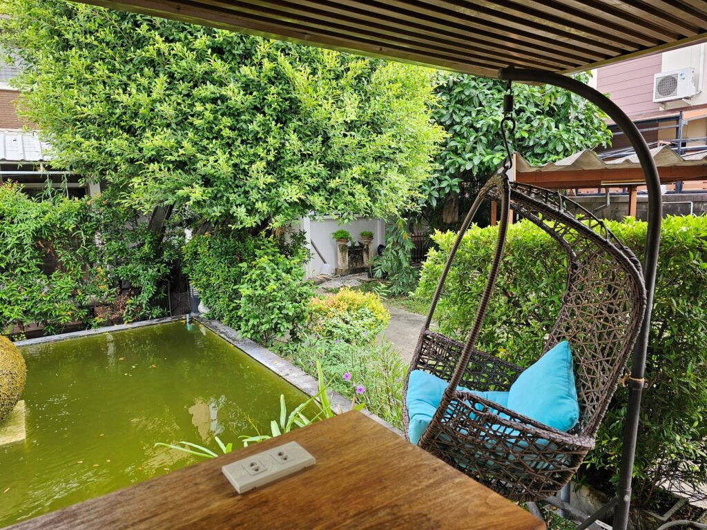 The gardens in the Princess Cafe in Bangkok. A water feature next to a swing chair beside a table with power outlets