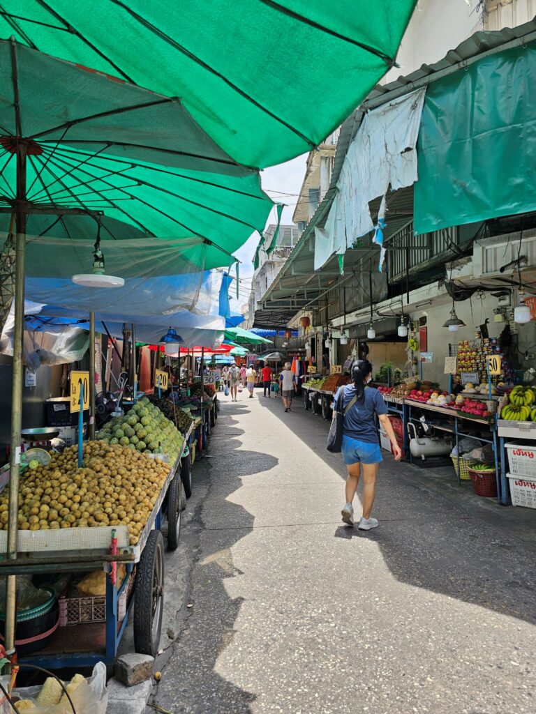 A street market selling produce, with large green umbrellas to protect from the sun.