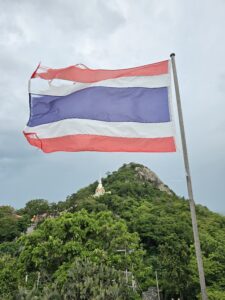 The Thai flag waving above a temple on a mountain