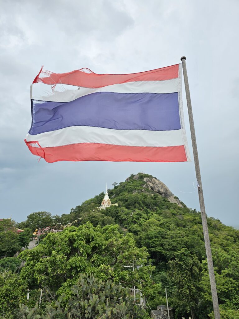 The Thai flag waving above a temple on a mountain