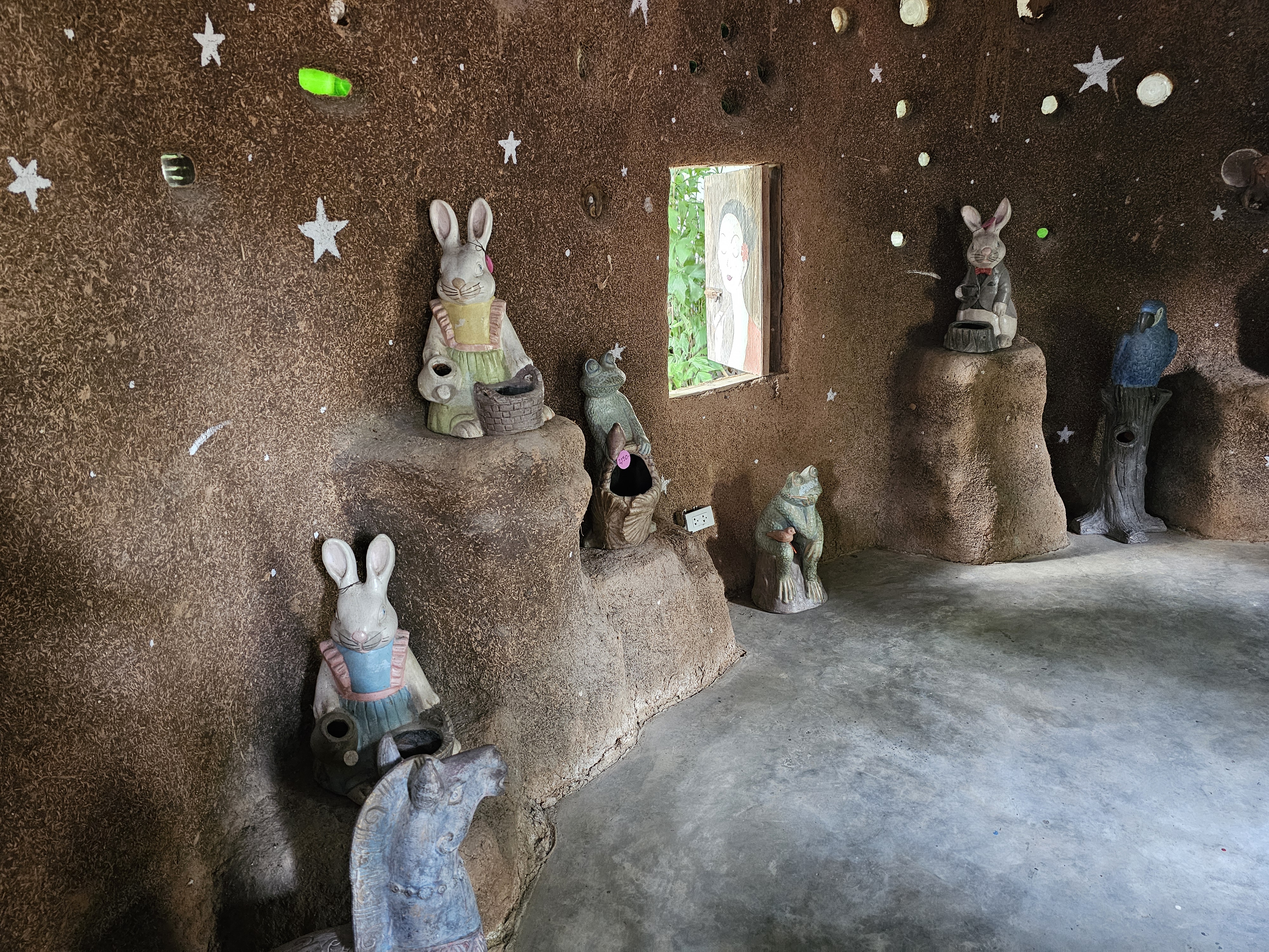 The interior of a small clay hut with many animal and anthropomorphic figures. Light comes in through the window and several holes in the walls.