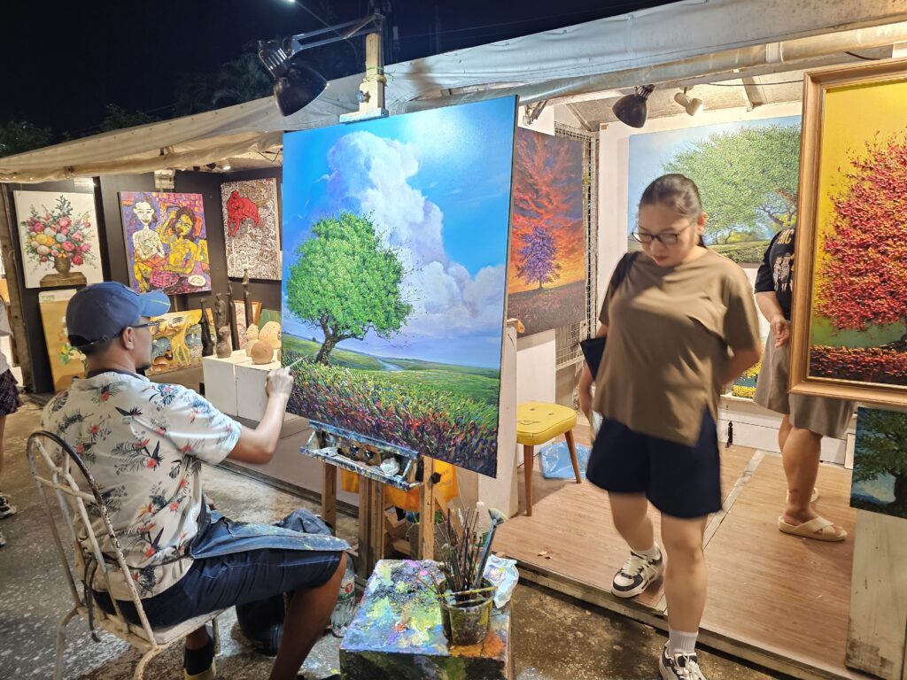 A Thai painter working on a painting during a night market