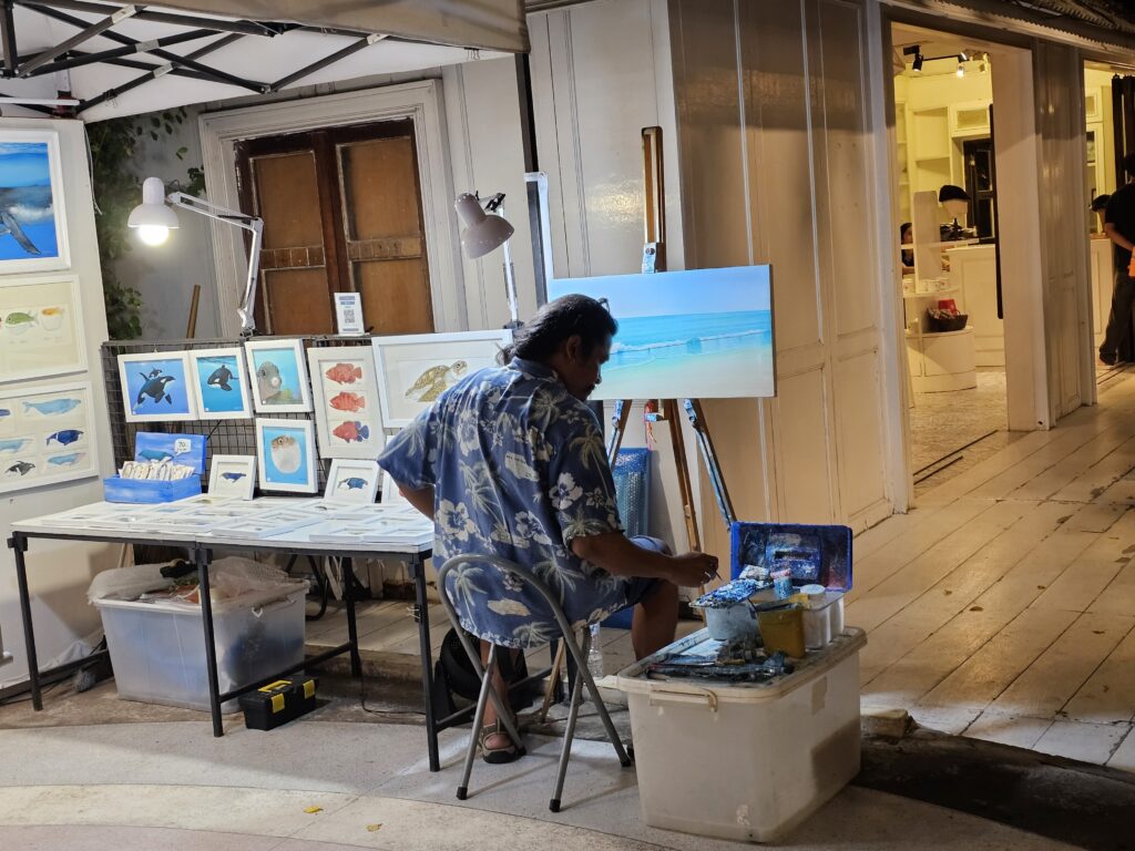 A Thai painter, working on a painting, at a night market
