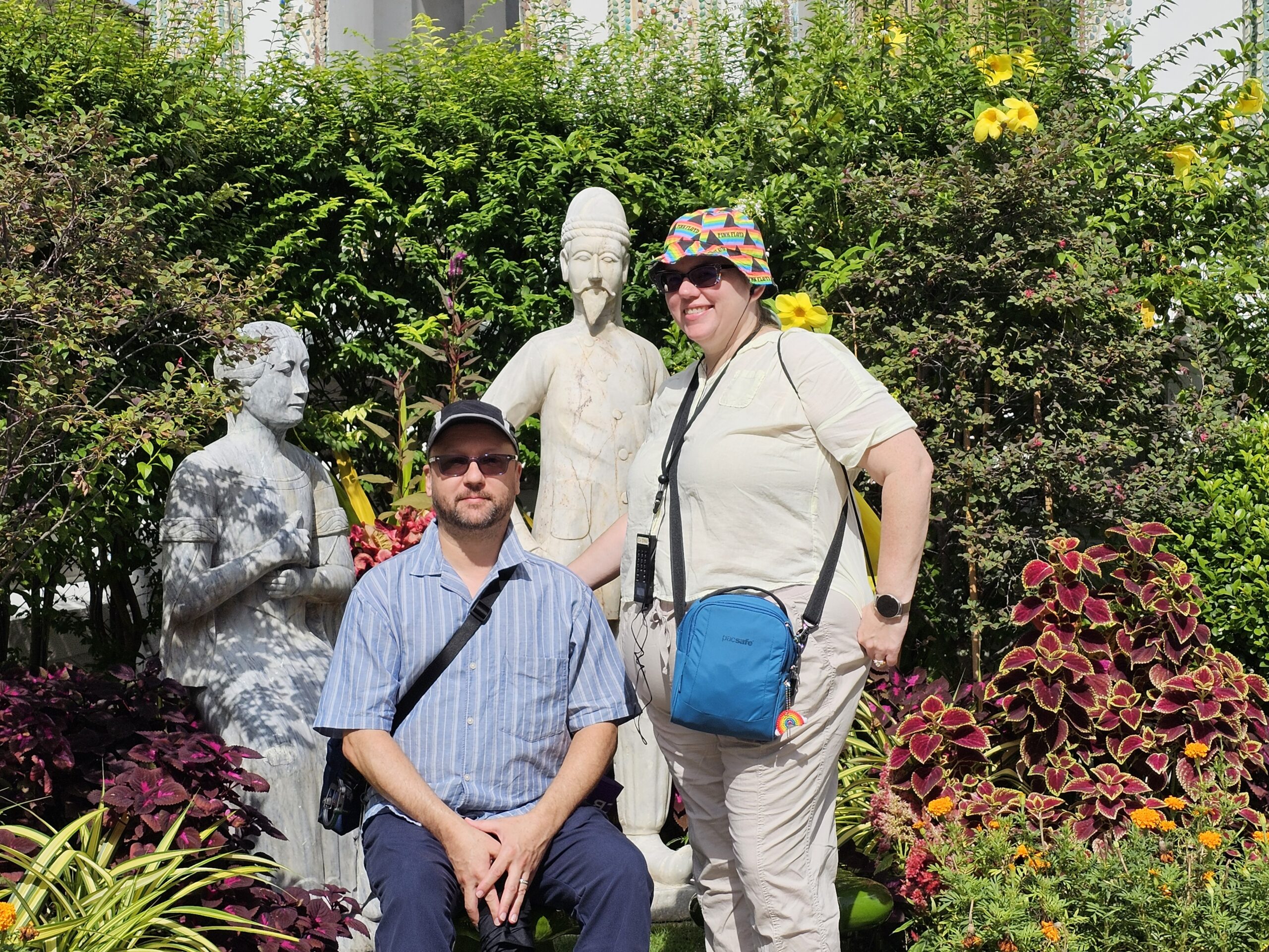 John and Stephanie, a white middle-aged couple, absolutely melting on the grounds of the Grand Palace, in front of a statue